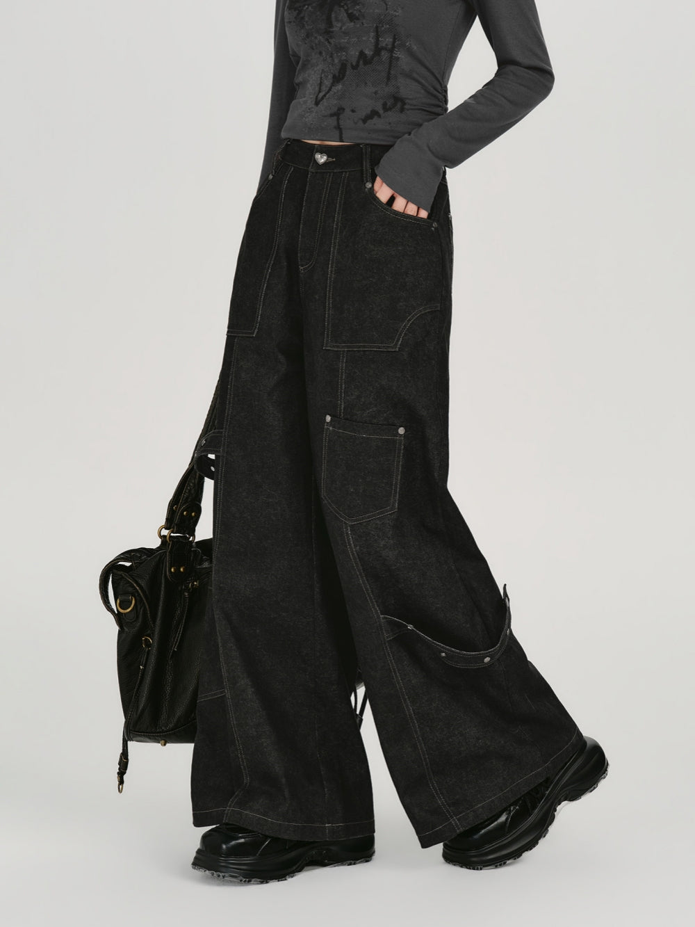 Black wide leg cargo jeans with white contrast stitching and utility pockets.