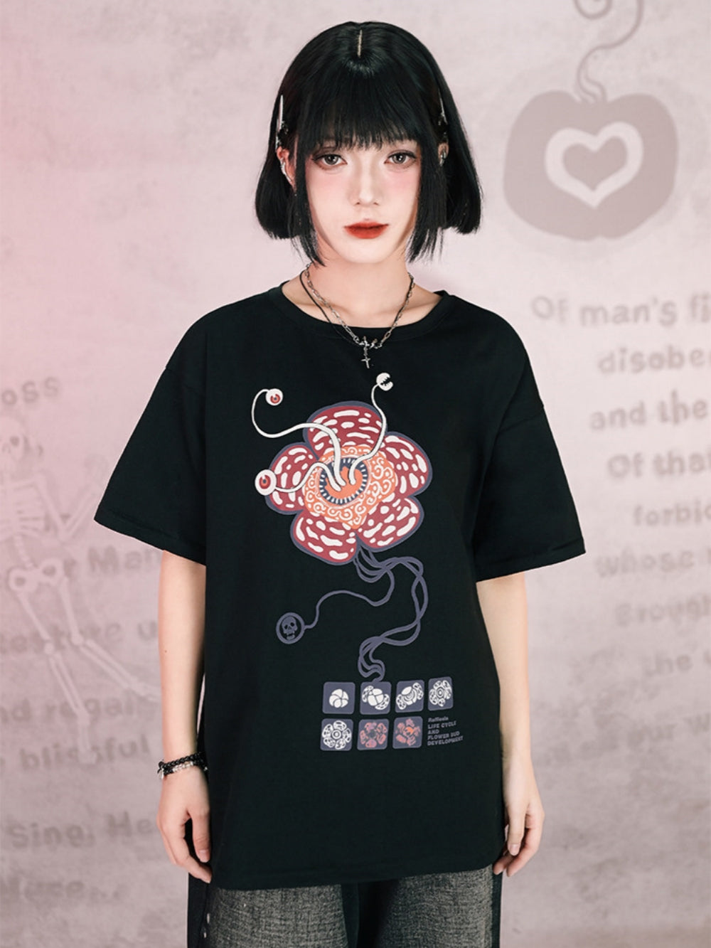 Oversized black streetwear t-shirt with a surreal rafflesia flower monster graphic featuring tentacles, eyeballs, and scientific botanical diagrams.