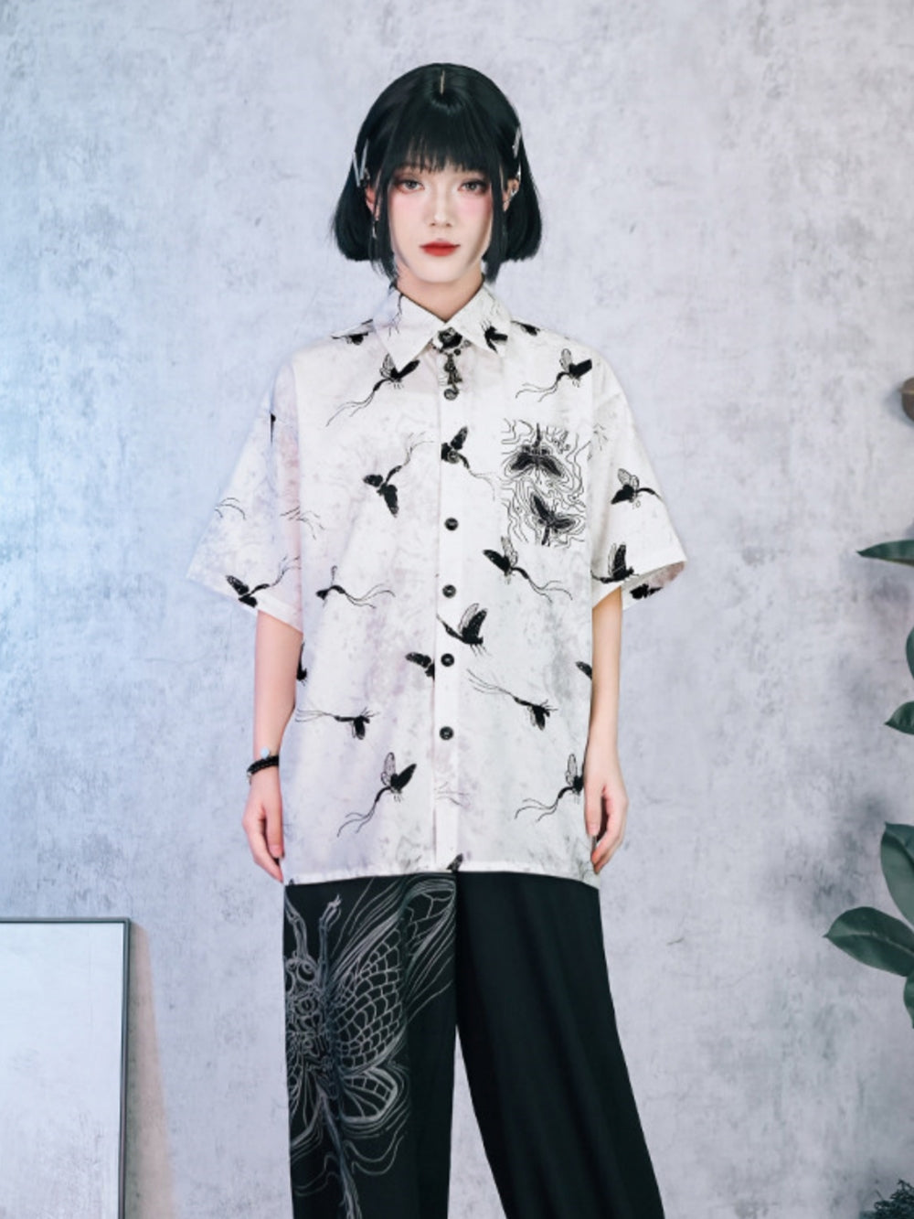 Unisex oversized short-sleeve button-up shirt in smoky marble white with all-over black moth and butterfly hand-drawn graphics.
