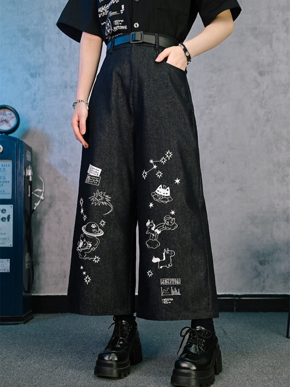 Person wearing Cyber Y2K baggy graphic jeans with white star and cat illustrations.