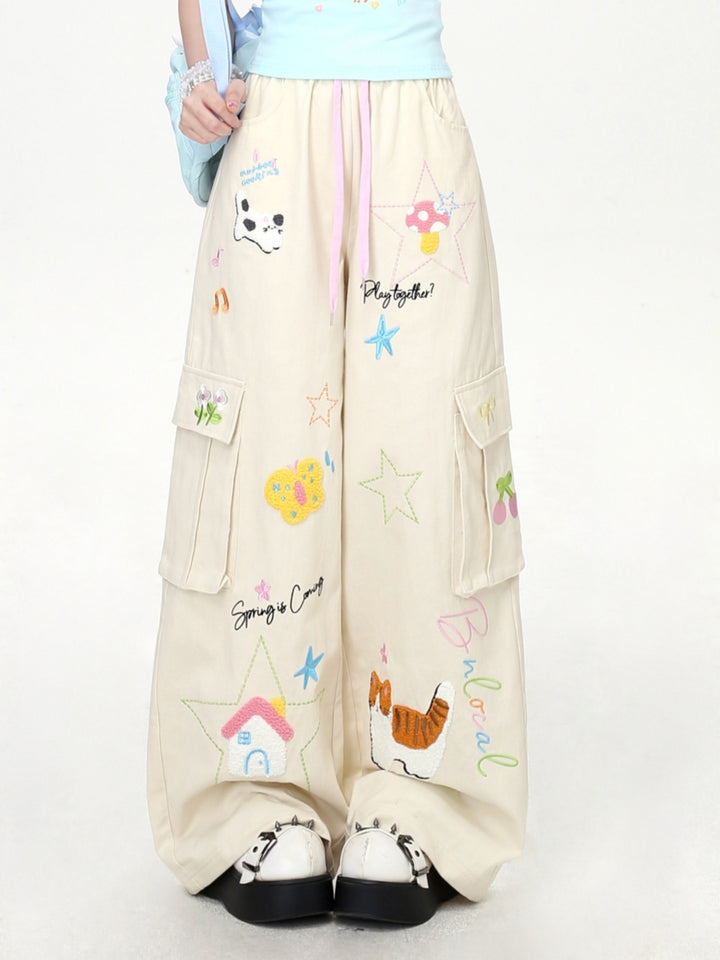 Model wearing cream and black Cyber Y2K kawaii baggy cargo pants with colorful cartoon character embroidery.