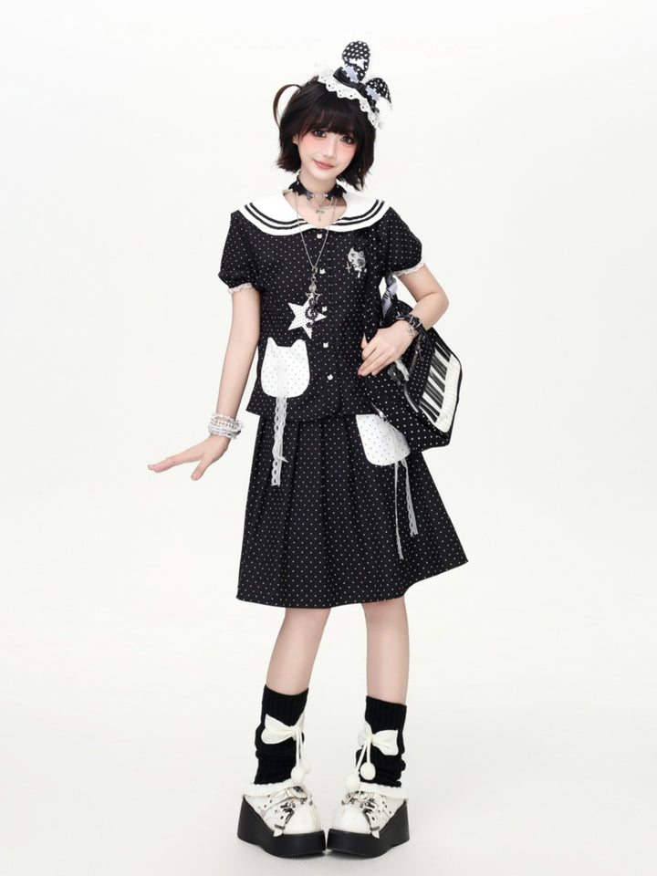 Model wearing a black polka dot Cyber Y2K kawaii sailor skirt set with a contrast white collar and cat patch pockets.