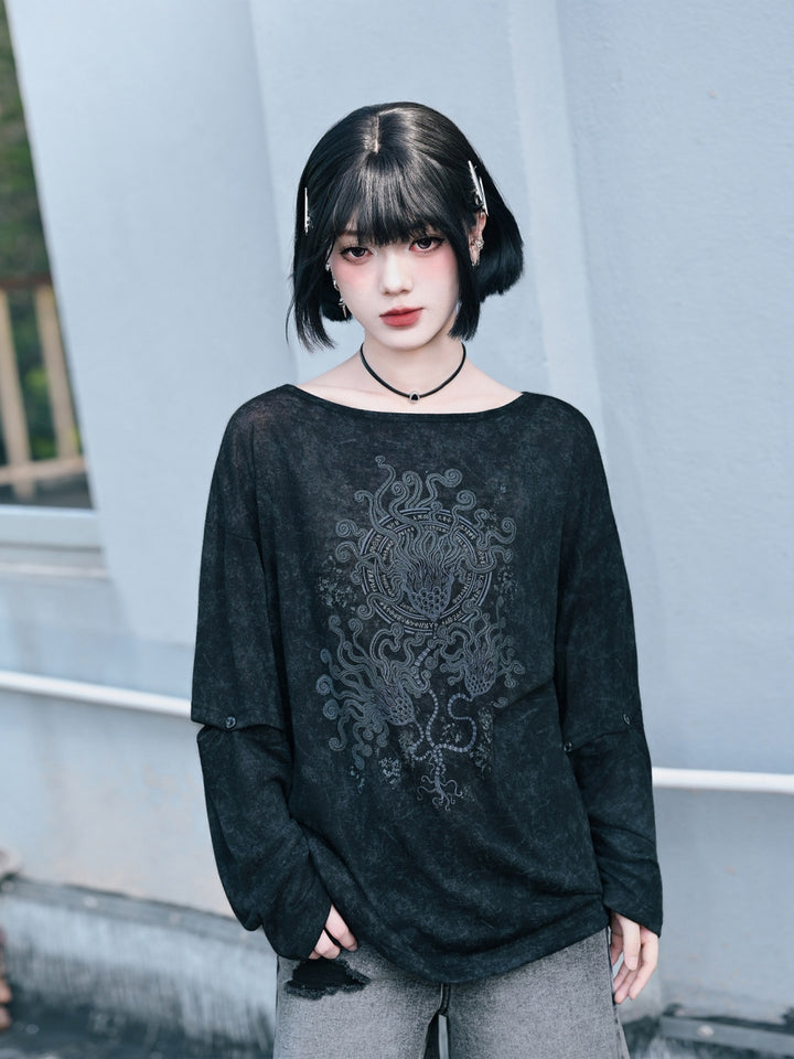 A model wearing a black cyber grunge long sleeve shirt with a faded acid-wash finish, an industrial graphic print, and modular button sleeves, styled for a gothic streetwear look.