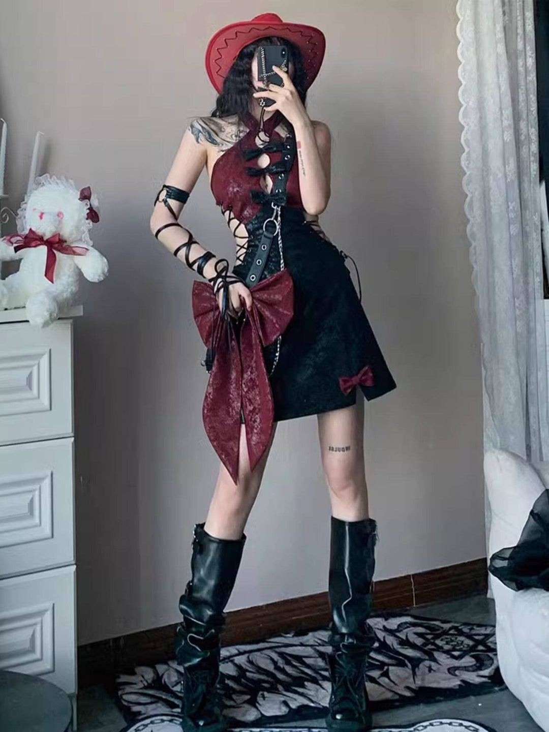Black and burgundy halter mini dress with bows between front cutouts, crisscross lacing at the waist sides, and burgundy bows above two small hem slits.