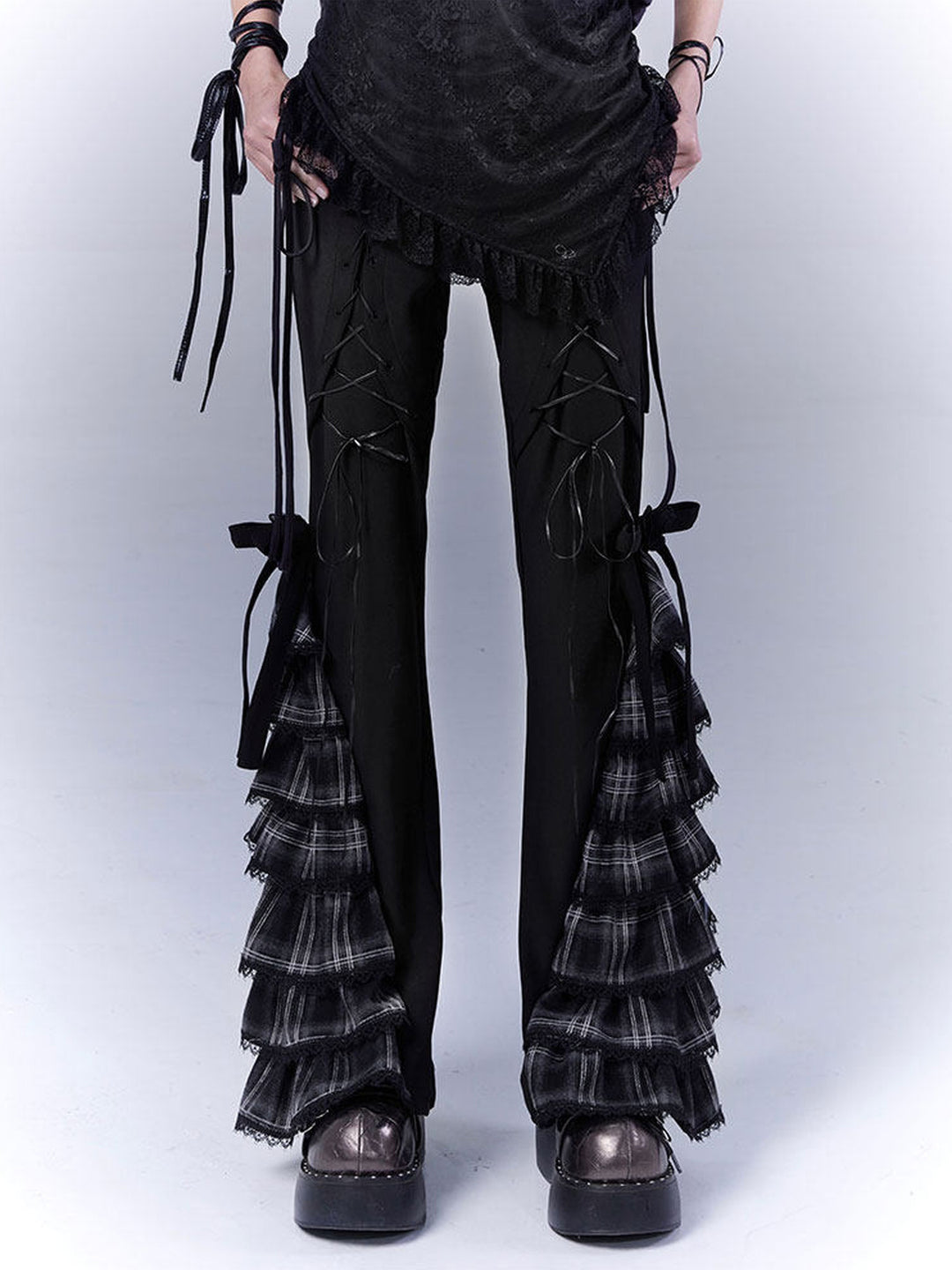 Black pants with crisscross lacing on the upper legs and tiered gray-and-black plaid ruffles widening the lower legs, topped by black bows.