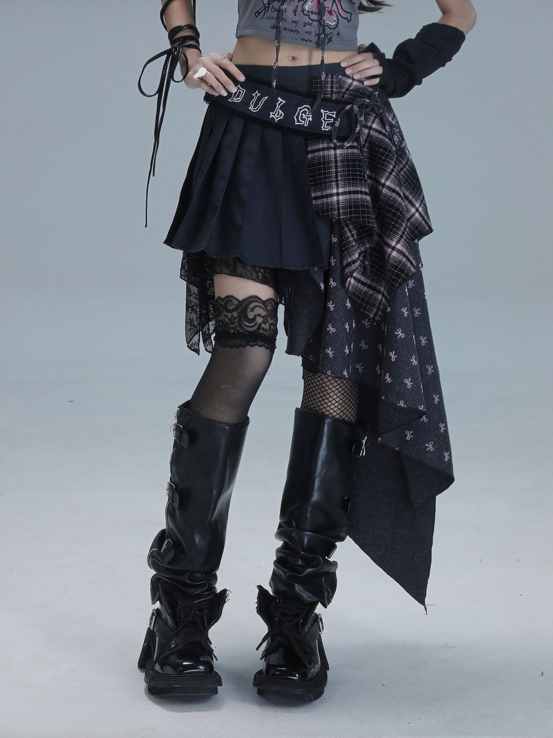 Black pleated punk skirt with plaid panels and a small bow-print section draping down one side to create a long asymmetric hem.