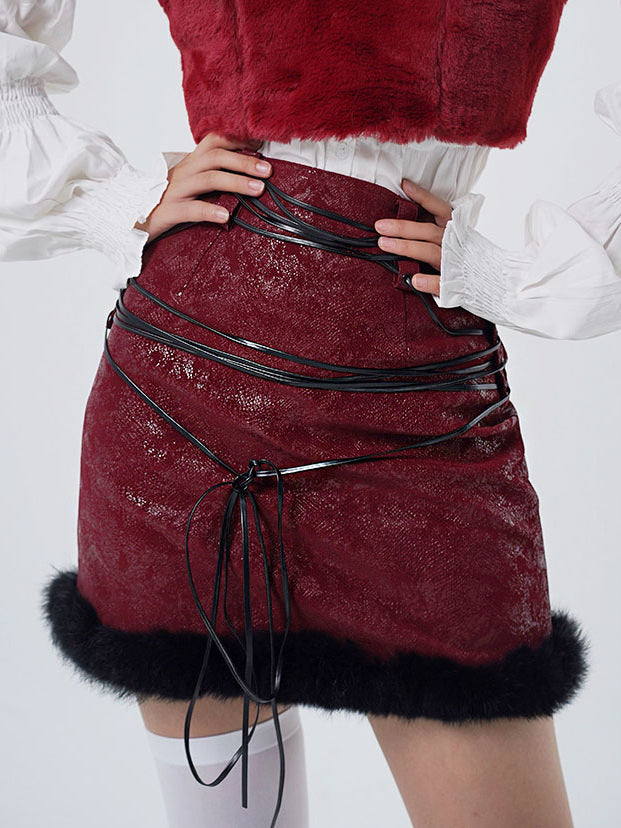 Burgundy mini skirt with black lacing through the waistband and cords crossing over the hips, ending in long front ties above a fluffy black hem.