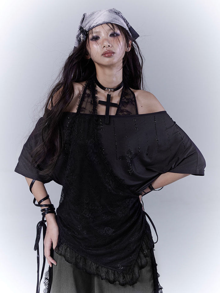 Charcoal-and-black off-shoulder top with studded lines and a cross motif above a draped floral overlay that gathers at one side and ends in a ruffled hem.
