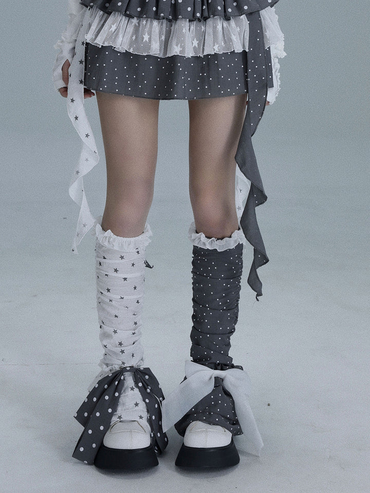 Mismatched gray and white leg warmers combine star and polka dot patterns, ruffled tops and oversized contrasting bows near the ankles.