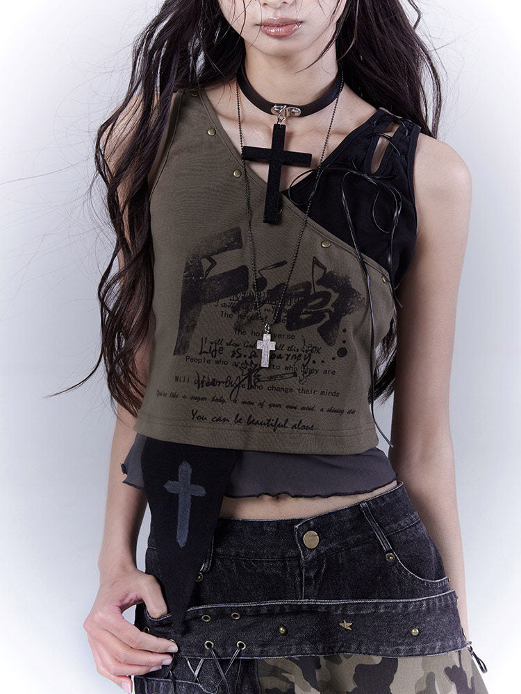 Olive-and-black graphic crop top with a studded diagonal seam, lacing at one shoulder and a gray underlayer extending below the hem beside a pointed cross panel.