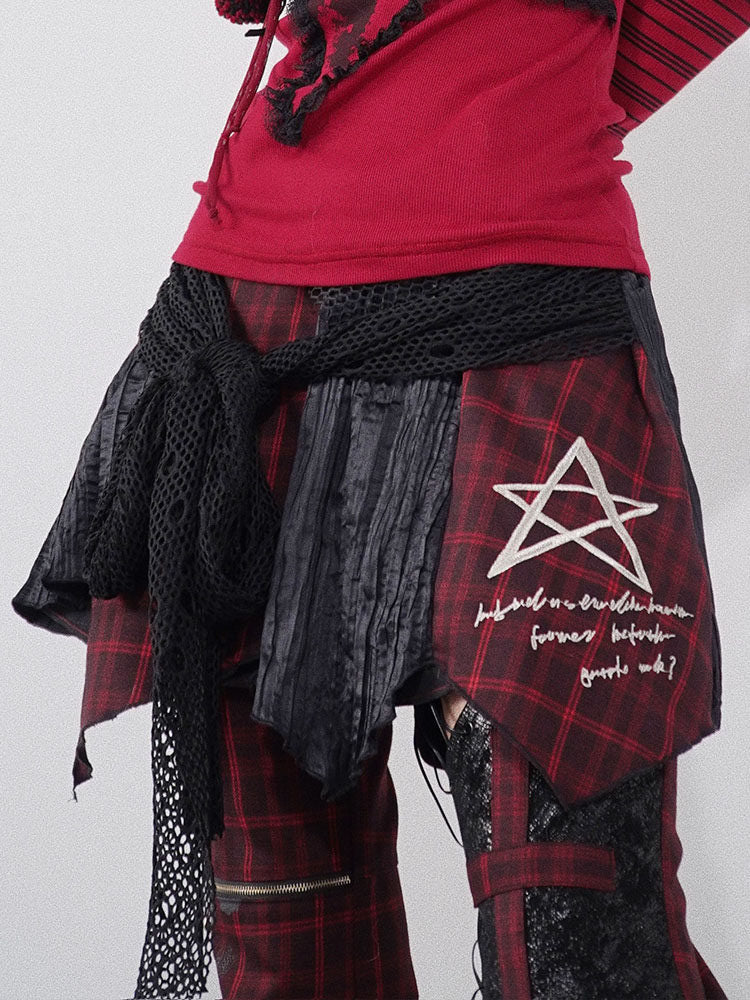 Red and black plaid punk skirt with layered black panels forming an uneven hem and a white outlined star above lettering on one side.